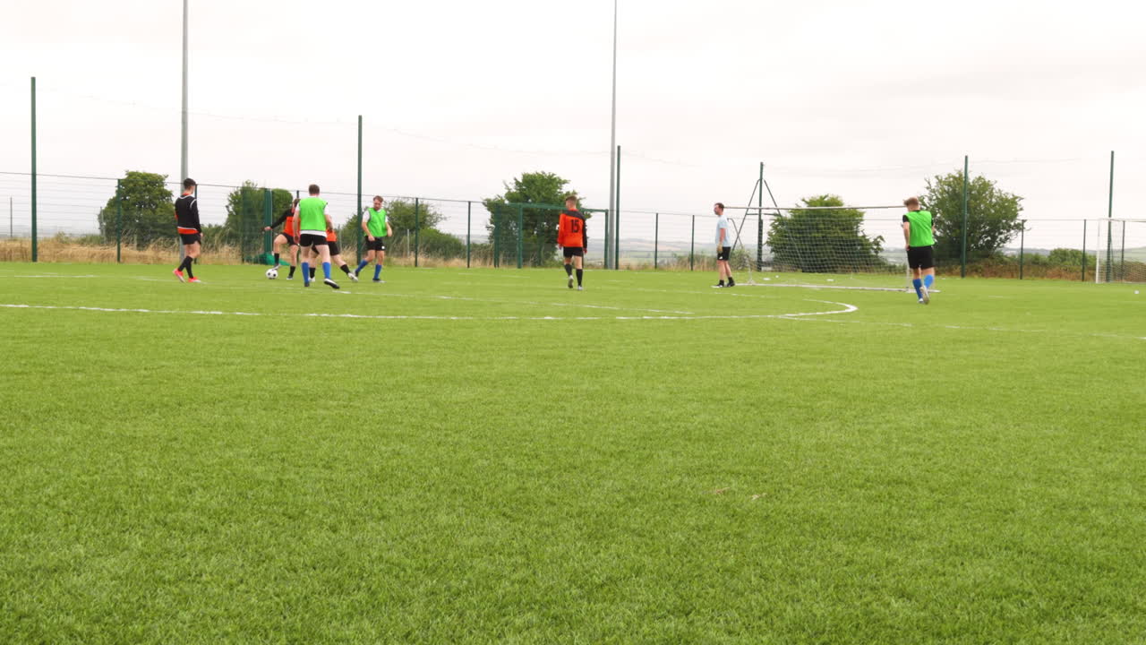 Practicing soccer on field, players wearing colorful jerseys, preparing for match