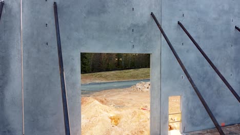 an ascending drone shot of the morning sun through a concrete panel on a construction site