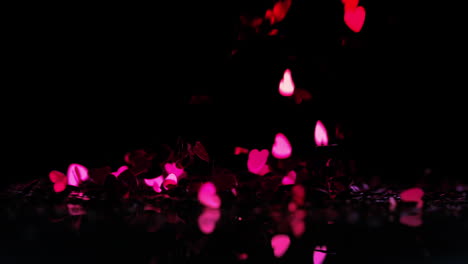 pink heart confetti falling down on black background