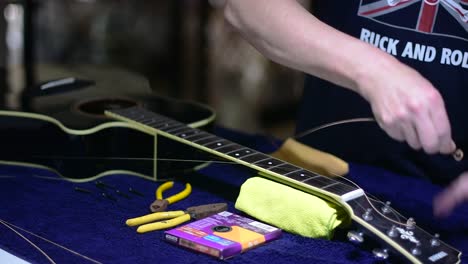 restringing and cleaning a beautiful black single cutaway accoustic guitar - unwinding the strings from the machine heads