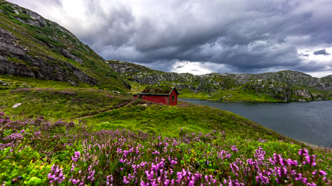 cabaña roja entre lago y montaña, movimiento de brezos y nubes, campo noruego