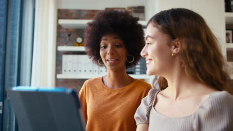 dos colegas de negocios femeninas con tableta digital se reúnen en la oficina