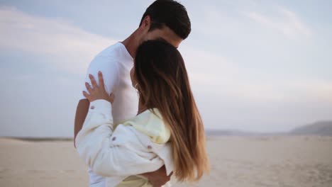 Nice-lovely-cheerful-couple-wearing-casual-white-T-shirts.-Dark-haired-guy-spinning-with-his-lady,-holding-hands-in-moves.-Dancing-on-nature-in-empty-desert.-Sensual-moves.-Slow-motion