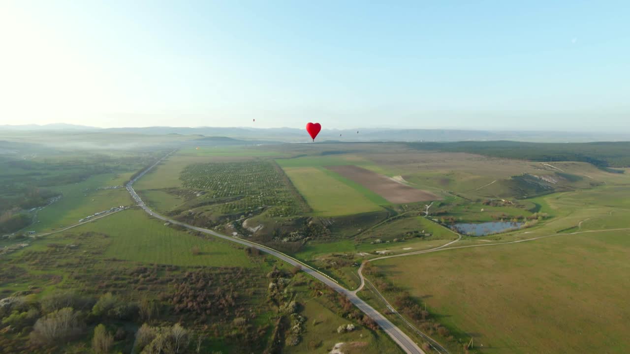 아름다운 시골 풍경 위에 심장 모양의 열기 풍선