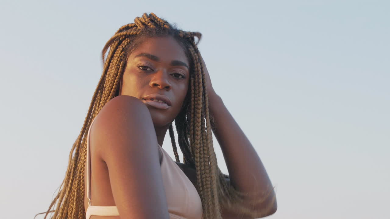 африканская девочка играет со своими косами на пляже