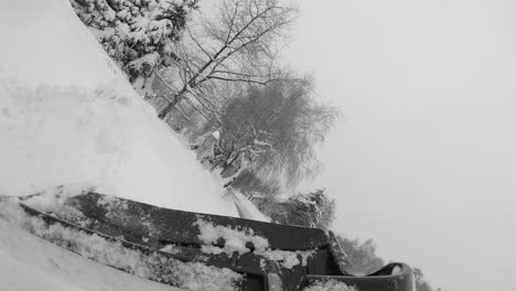 Removing-snow-from-driveway-with-large-shovel,-slow-motion-pov