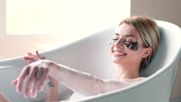 donna che si rilassa in un bagno a bolle con maschere per gli occhi
