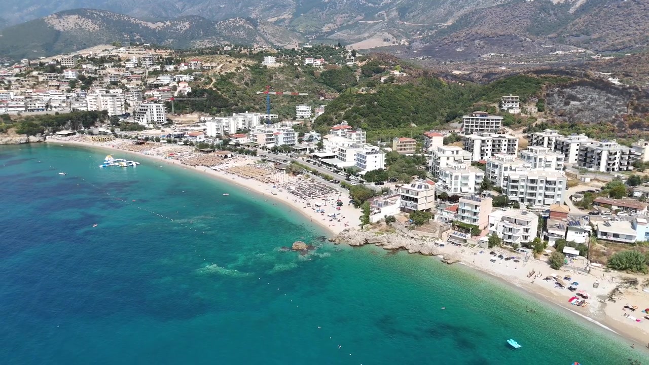 Vista aérea de drone dos hotéis à beira-mar de Dhermi, Albânia, mar Jônico turquesa e vila costeira da Riviera Albanesa