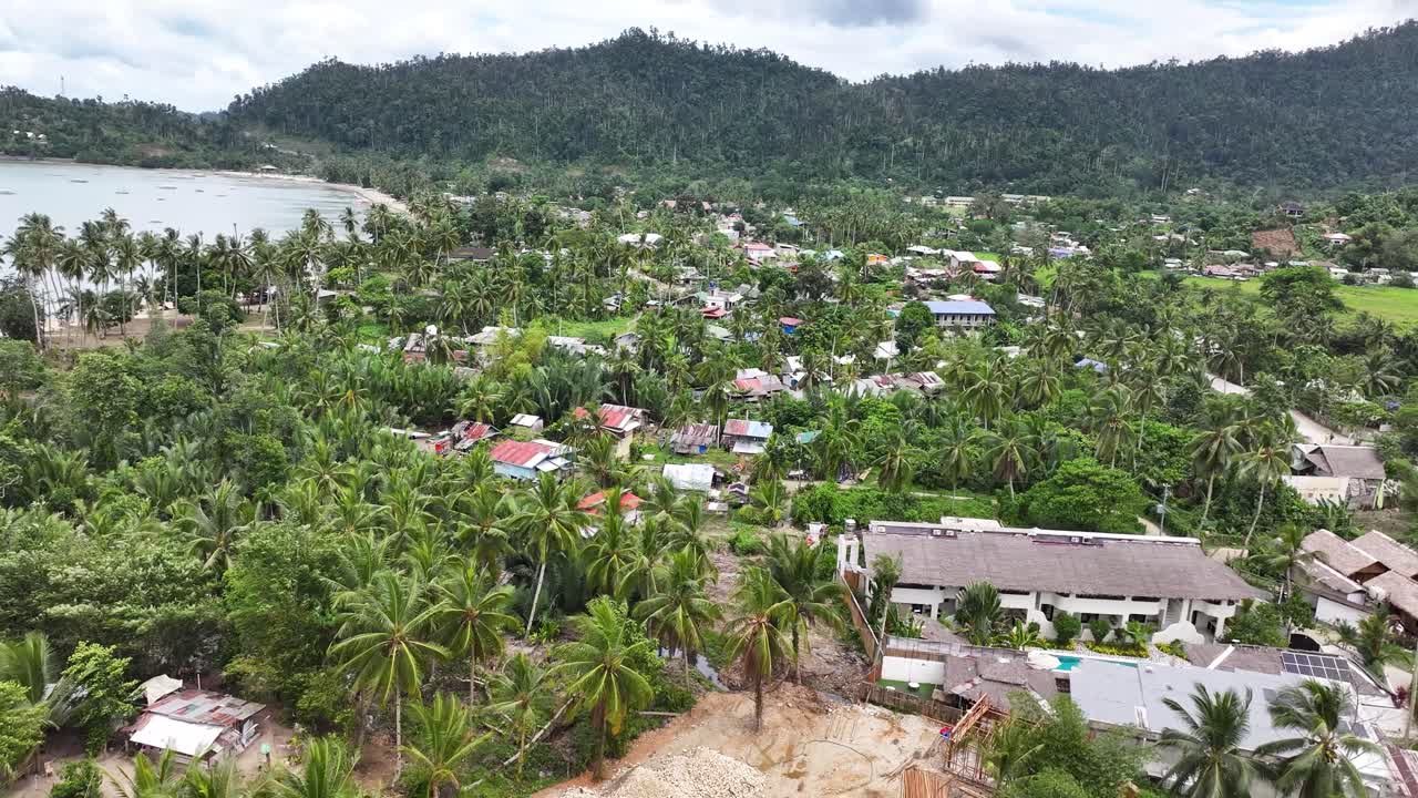 Aerial over village in Port Barton with small houses and community buildings, Philippines.