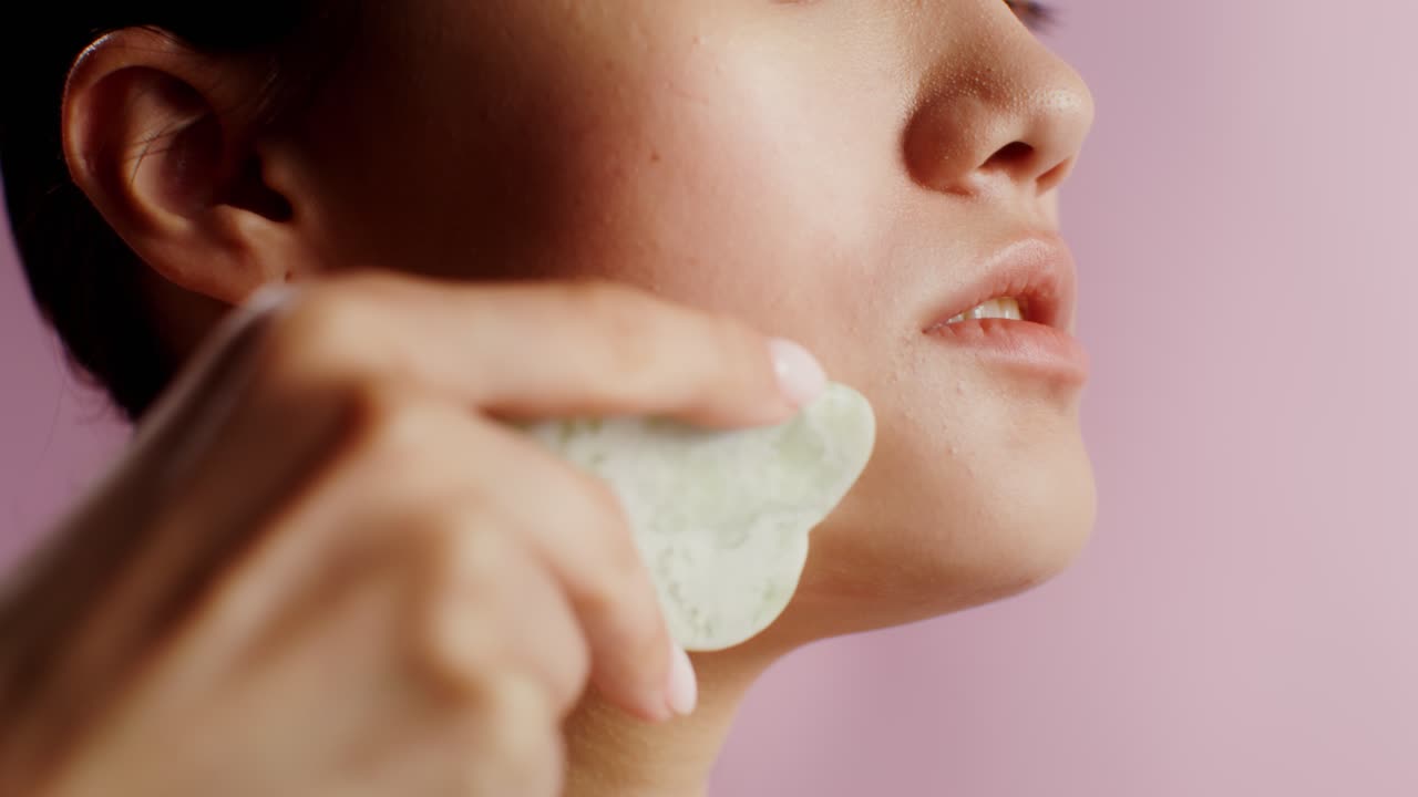 Woman using Gua Sha for facial massage