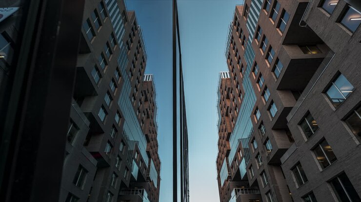 Edifício de vidro espelhado reflexivo contra o céu azul do pôr do sol no Projeto Barcode, Centro de Oslo, Noruega - ângulo baixo, time-lapse
