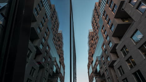 Edificio-De-Vidrio-De-Espejo-Reflectante-Contra-El-Cielo-Azul-Del-Atardecer-En-El-Proyecto-De-Código-De-Barras,-Centro-De-Oslo,-Noruega---ángulo-Bajo,-Lapso-De-Tiempo