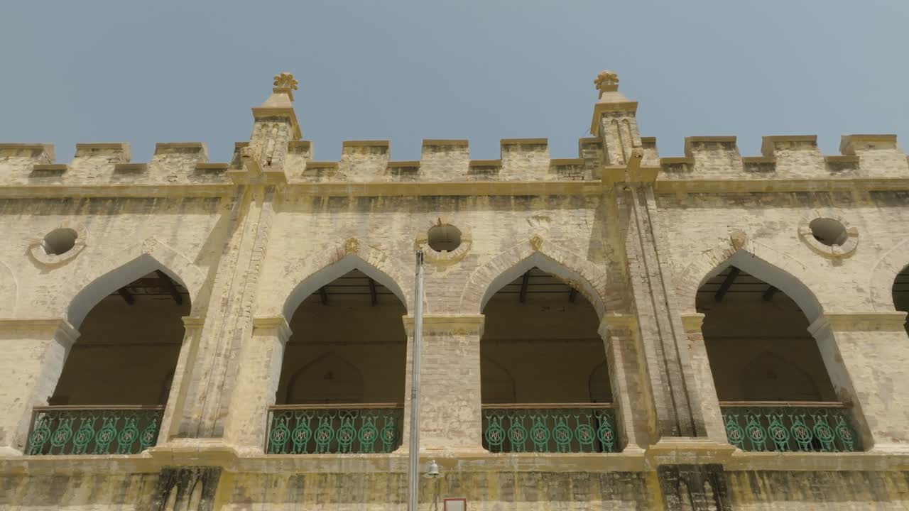 Historic Gothic-style building with pointed arches, crenellated parapets, and ornate finials. Weathered stone and green iron railings evoke colonial charm and architectural elegance