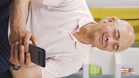 Vertical-video-of-Od-man-smiling-at-phone-message.