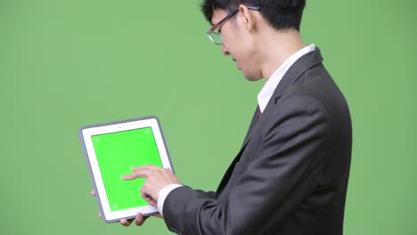 젊은 행복한 아시아 사업가들이 디지털 태블릿을 카메라와 터치 스크린에 보여주고 있습니다.