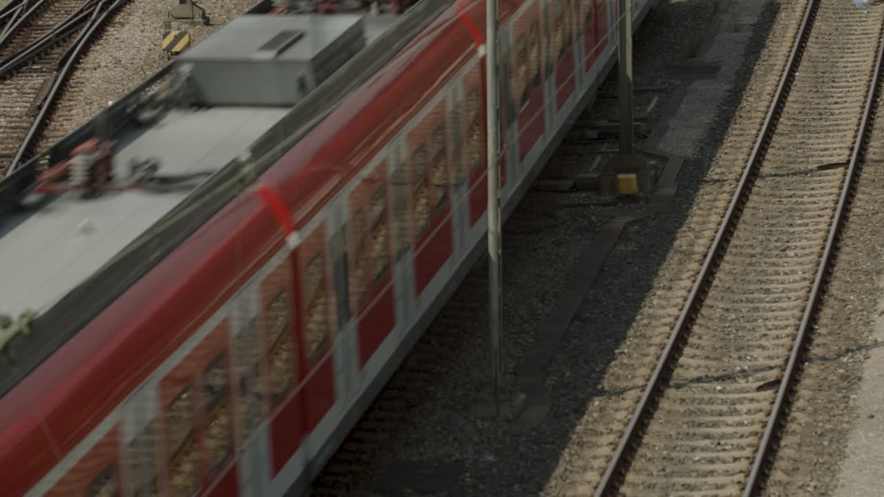 A red Deutsche Bahn train moves on multiple railway tracks in an industrial setting