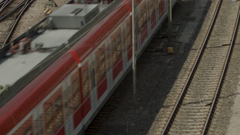 a red deutsche bahn train moves on multiple railway tracks in an industrial setting