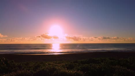 uhd hawaii kauai timelapse static of sunrise over the ocean with a few people on beach in distance on partly cloudy morning
