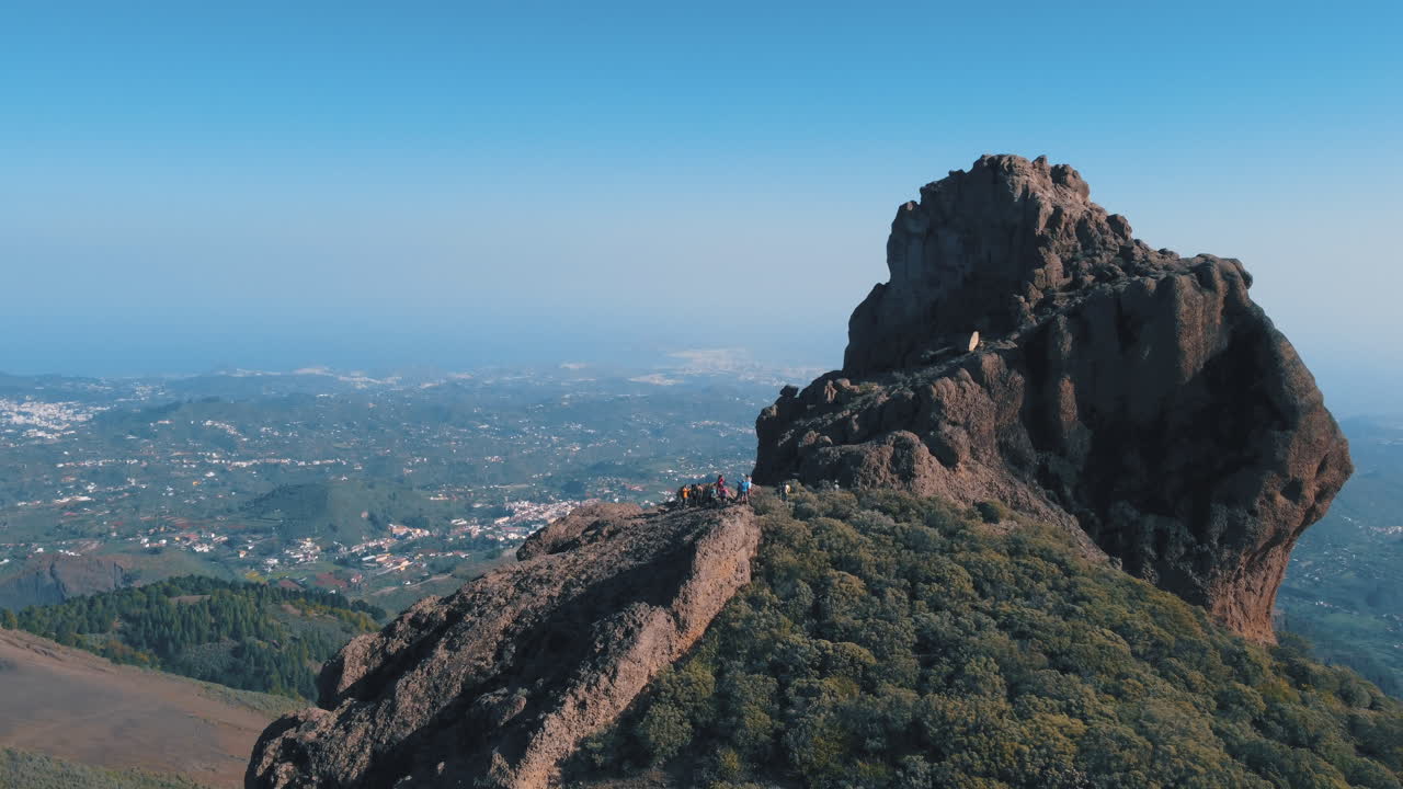 toma aérea en la distancia y revelando el roque saucillo y donde hay un grupo de turistas bajando la montaña