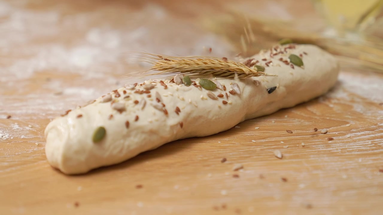 Cospargere vari semi sull'impasto di pane crudo con una spiga di grano