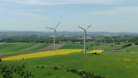 Aufsteigender-Dolly-Aus-Der-Luft-Zu-Windmühlenturbinen-Im-Windpark-über-Rapsfeldern