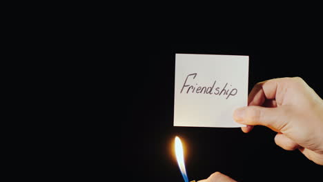손은 비문 우정으로 불타는 종이를 보유하고 있습니다.