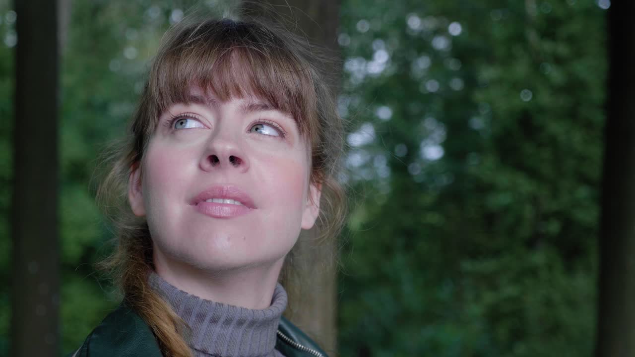 hermosa niña sonríe y mira a su alrededor en el bosque sombreado, primer plano