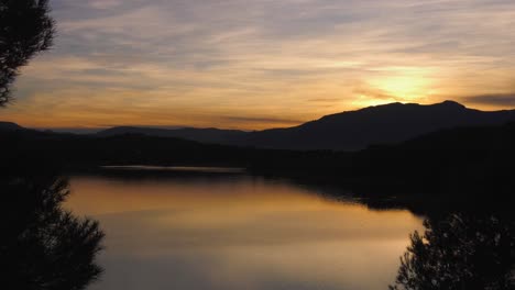 Sunset-reflecting-in-calm-lake-timelapse