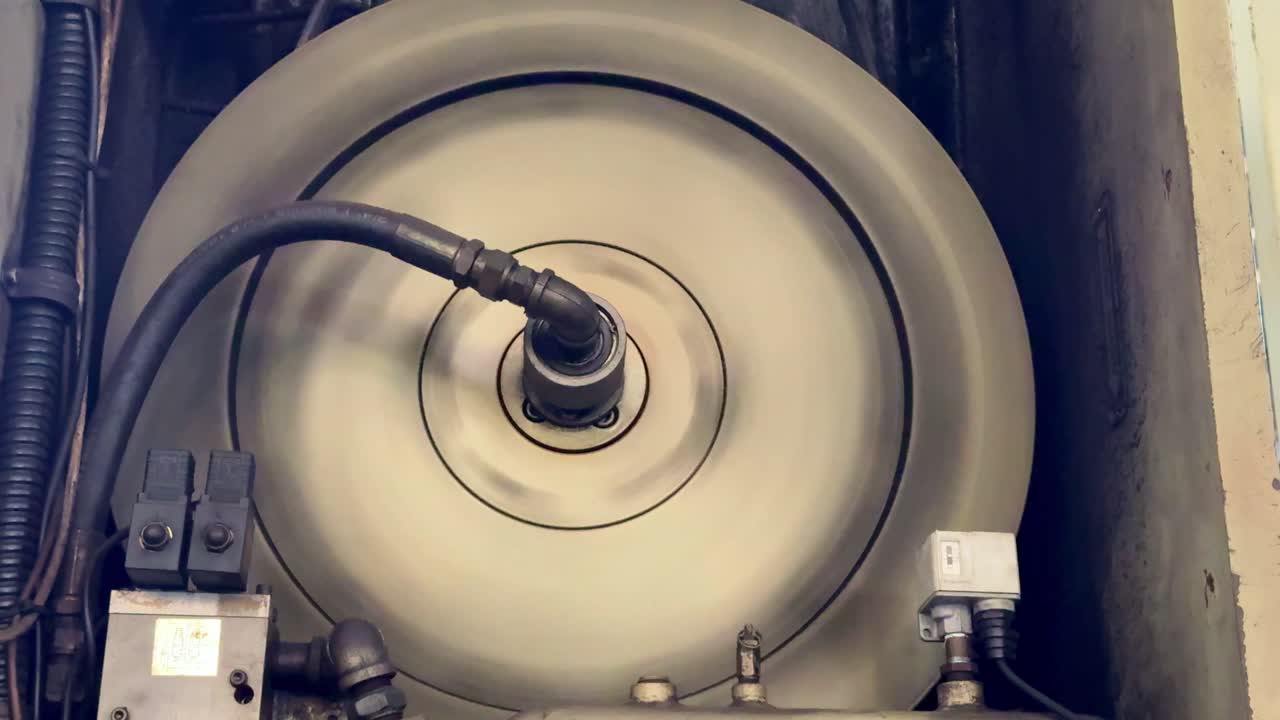 Close-up view of a rotating industrial machine part in operation, showing mechanical movement and precision engineering in a factory environment. Concept of heavy industry, machinery, and engineering