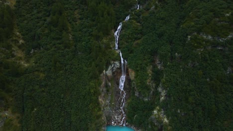 Drone-shot-flying-over-the-Place-de-Moulin-reservoir-panning-up-to-reveal-a-waterfall-and-the-mountainside