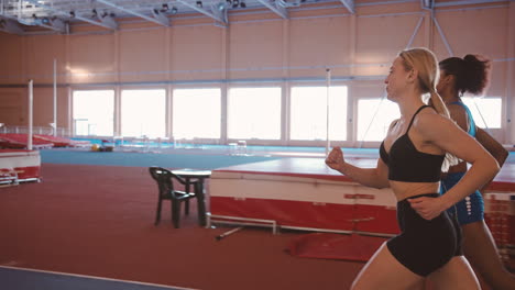 two multiethnic female athletes running together on an indoor track 1