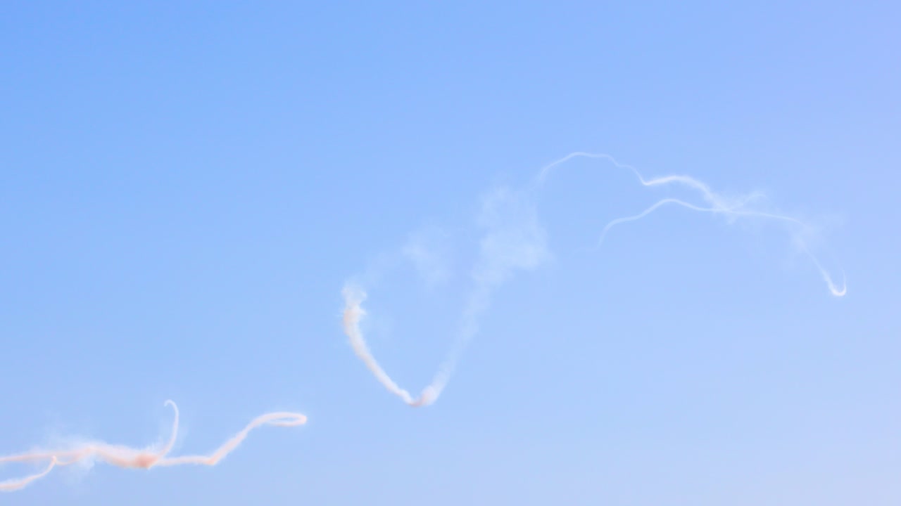 Aerobatic aircraft create intricate smoke patterns against a clear blue sky in Geelong, Australia, showcasing dynamic aerial maneuvers