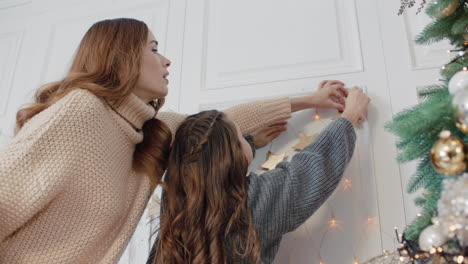 Concentrated-mother-decorating-living-room-with-teen-daughter-together.