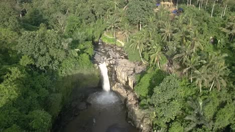 vista aérea del carro ascendente hacia atrás de una cascada, cascada de tegenungan en bali, indonesio, con bosque circundante