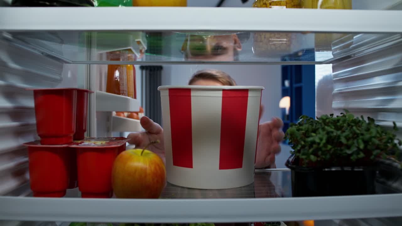 niño comiendo pollo frito en el refrigerador