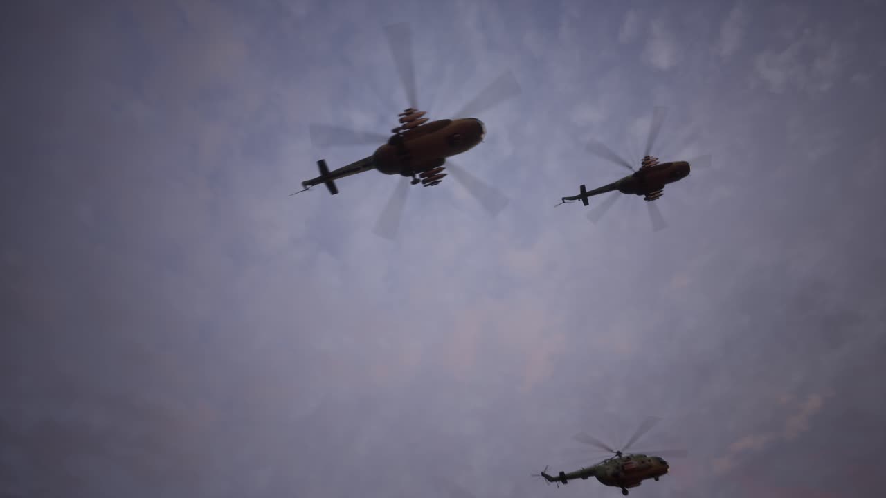 Formazione di elicotteri militari che volano al tramonto o all'alba attraverso un cielo nuvoloso.
