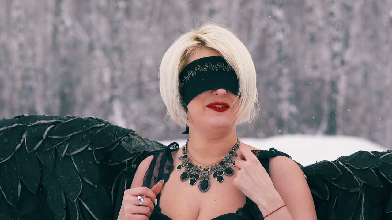 dama con alas negras juega al ave fénix en el bosque de invierno