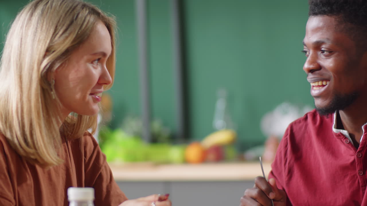 젊은 다민족 부부 가 집 에서 식사 하는 동안 대화 하고 있다