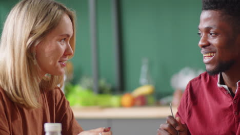 Joven-Pareja-Multiétnica-Charlando-Durante-La-Comida-En-Casa