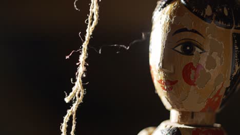 an enigmatic puppet captured in two frames: a close-up of an intricate wooden figurine expressing emotion and character with a tangled thread