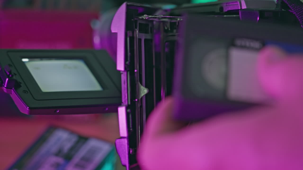 Hand Inserting and Removing MiniDV Cassette from Vintage Camcorder with Neon Light