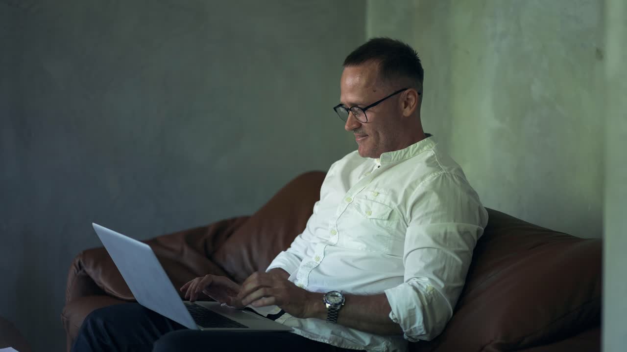 hombre de negocios sonriente trabajando en una computadora portátil en la oficina de casa. hombre profesional escribiendo en el teclado de la computadora portátil en el lugar de trabajo de la oficina