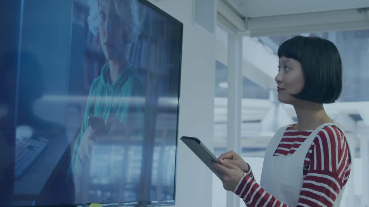 Animation of bar graph over asian woman looking at television and using digital tablet in office