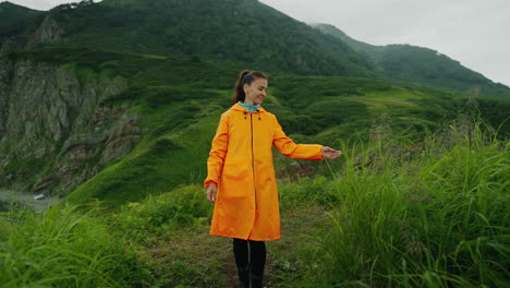 woman hiking in mountains with orange rain jacket