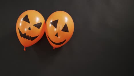 Two-halloween-pumpkin-printed-balloons-with-copy-space-on-black-background