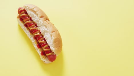 video of hot dog with mustard and ketchup on a yellow surface