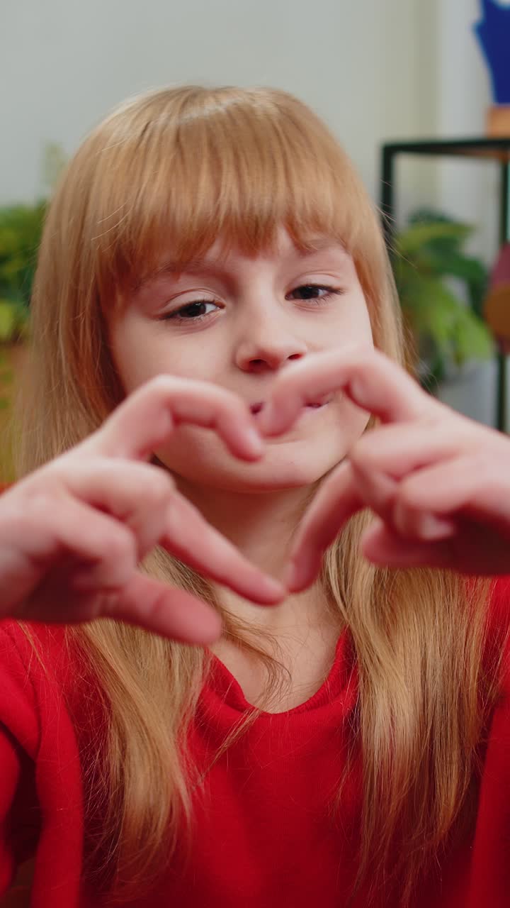 Una ragazzina fa il simbolo dell'amore mostrando il segno del cuore alla telecamera per esprimere i sentimenti romantici