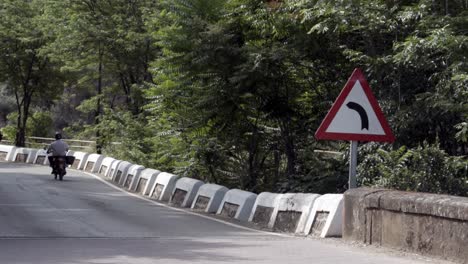 Old-and-fat-man-rides-a-motorcycle-next-to-a-traffic-signal-on-a-rural-road