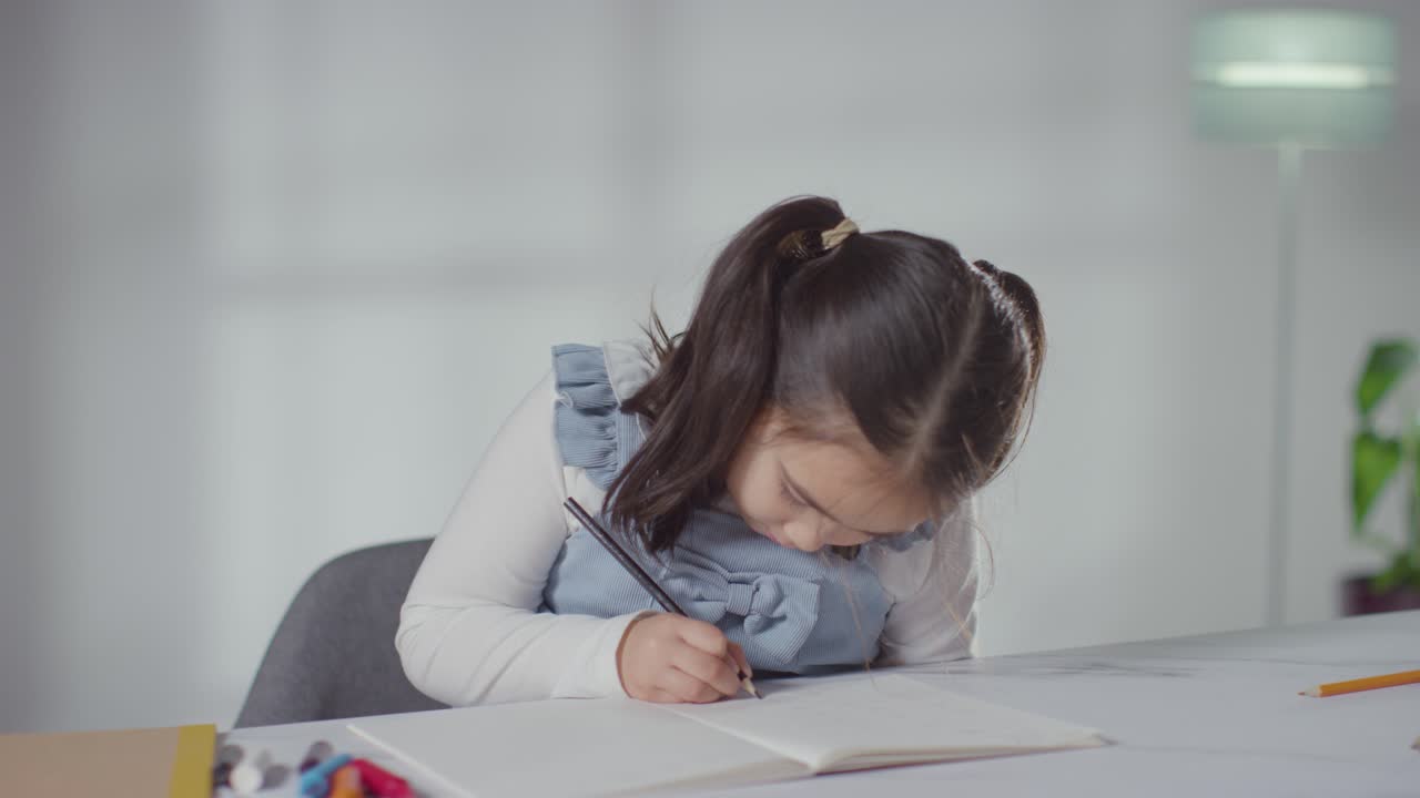 Young Girl On ASD Spectrum At Table At Home Concentrating On Writing In School Book 3