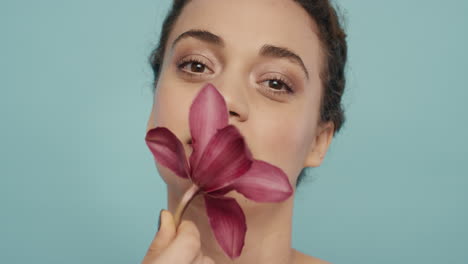 retrato de una mujer hermosa tocando juguetón el rostro con una flor de orquídea acariciando la piel perfecta disfrutando de la suave fragancia de la esencia natural concepto de cuidado de la piel saludable